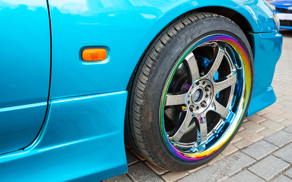 Modern blue sport car fragment, wheel on colorful metallic disc, closeup photo with selective focus and shallow DOF